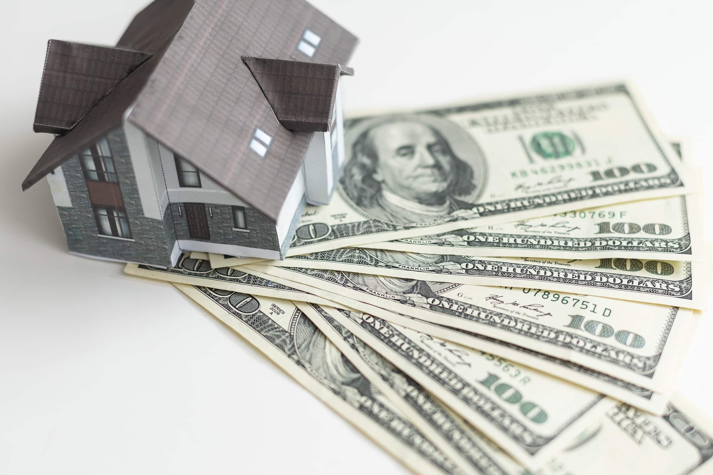Model house with hundred dollar bills spread around it