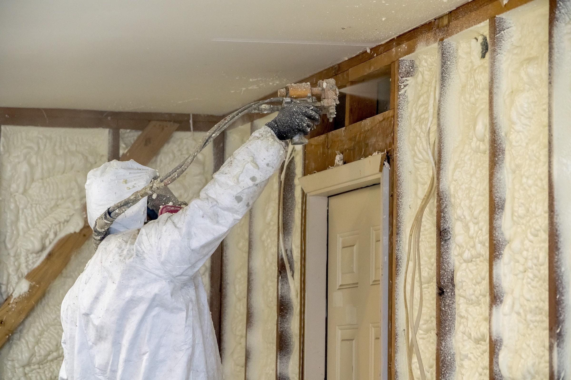 Worker applying spray foam insulation in wall cavities